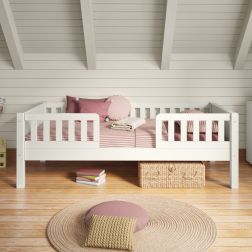 Closer view of Arven white Junior Bed with safety guard rails styled with muted pink bedding in a Scandinavian-style bedroom with panelled walls.