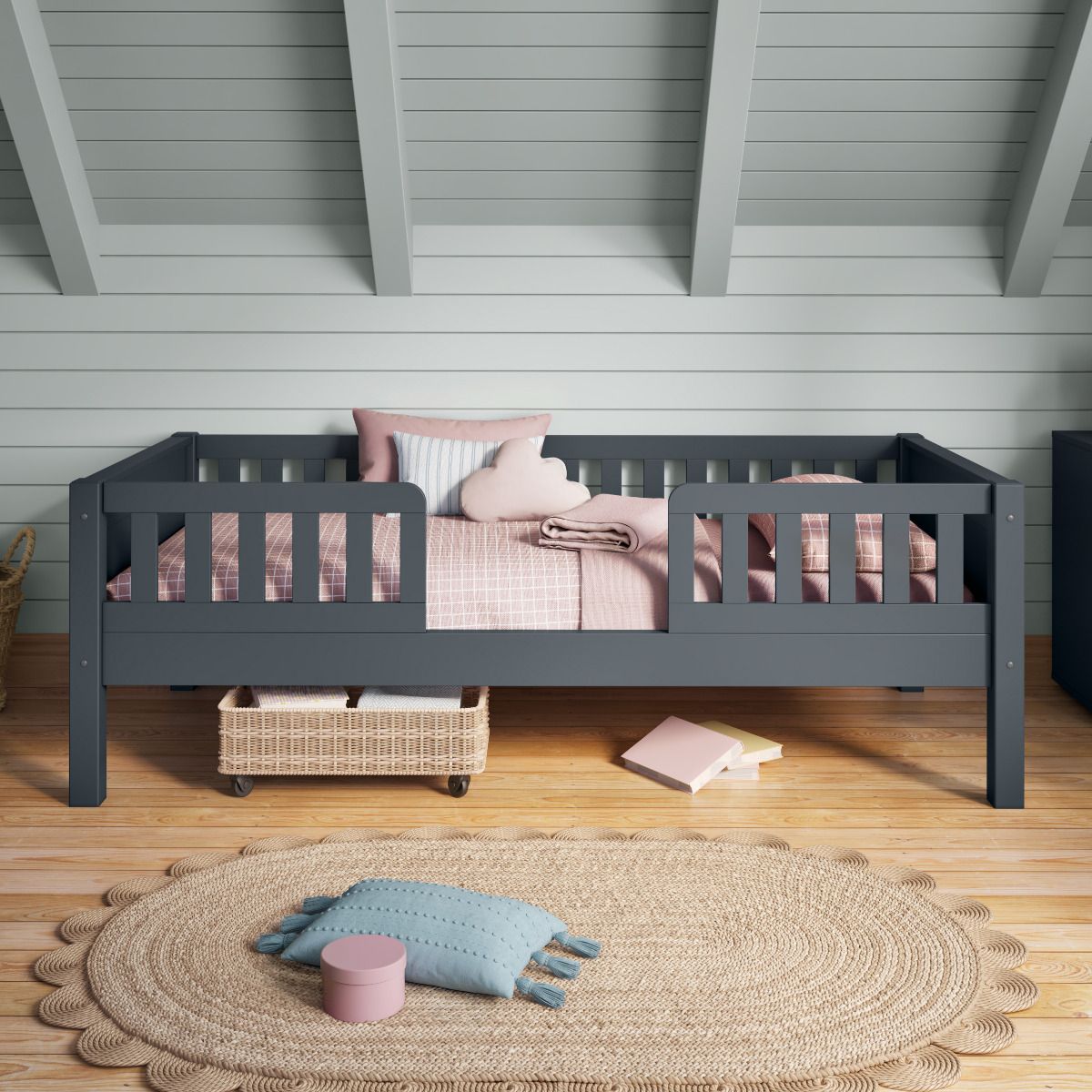 Closer front view of Arven blue Junior bed with safety guard rails styled with soft pink bedding in a Nordic style bedroom with tongue and groove soft blue painted walls.