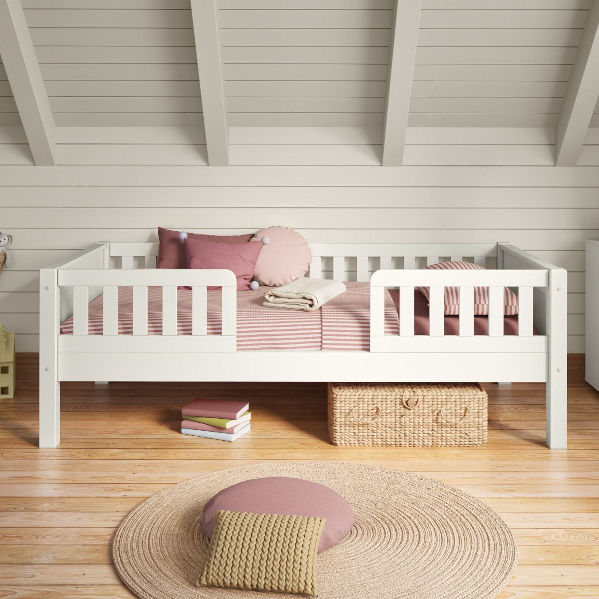 Closer view of Arven white Junior Bed with safety guard rails styled with muted pink bedding in a Scandinavian-style bedroom with panelled walls.