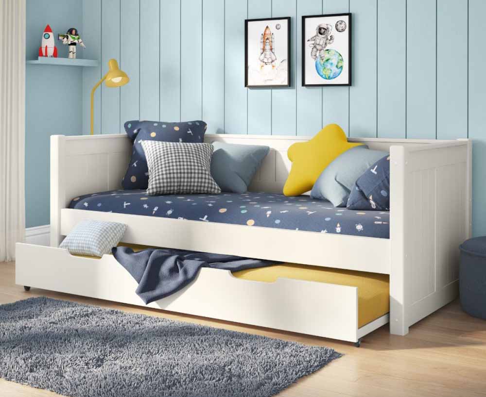 A white daybed with tongue and groove details in the headboards featuring an open trundle with mattress under the bed.
